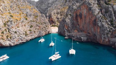 Serra De Tramuntana, Sa Calobra, Torrent De Pareis plajı, Akdeniz 'in havadan, kristal berrak suları kıyıya doğru giden yelkenli tekneler ve yatlar.