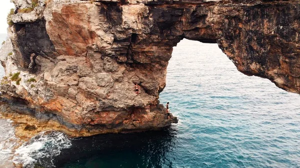 Es Pontas, touriste grimpant sur Natural Rock Arch à la côte de l'île de Majorque, entre Cala Santanyi et Cala Llombards, Espagne — Photo