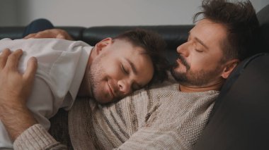Genç adam erkek arkadaşının kollarında uyuyor. Mutlu homoseksüel ilişkiler