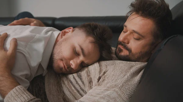Страстные объятия между двумя гомосексуальными партерами. Мужчины отдыхают на диване — стоковое фото
