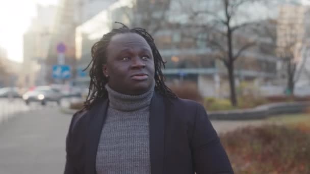 Porträt eines afrikanisch-amerikanischen schwarzen Mannes mit geflochtenen Haaren, der auf der Straße spaziert und sich umschaut — Stockvideo