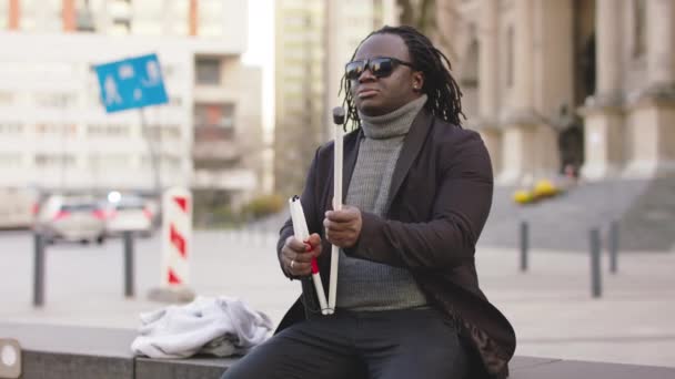 Ciego africano americano negro hombre abrir su caminar palo mientras sentado en el banco — Vídeo de stock