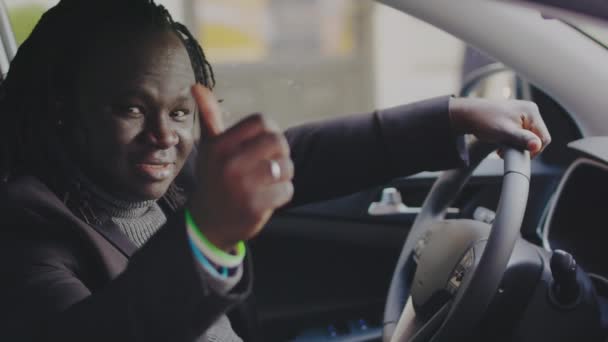 Kupuję nowy samochód. Młody afrykański czarny biznesmen siedzi na foteliku kierowcy i pokazuje kciuk w górę — Wideo stockowe