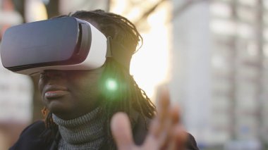Sanal gerçeklik. Şehir sokaklarında VR kulaklıklı siyah bir adam var.