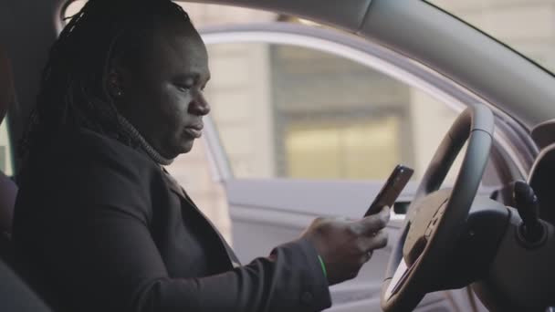 Udany Afrykański Amerykanin dostaje wiadomość tekstową zaskoczony siedząc na fotelu kierowcy swojego samochodu — Wideo stockowe