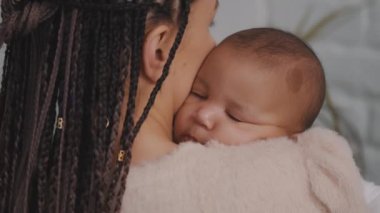 Anne kucağında tatlı uyuyan bir bebek. Çok ırklı aile kavramı