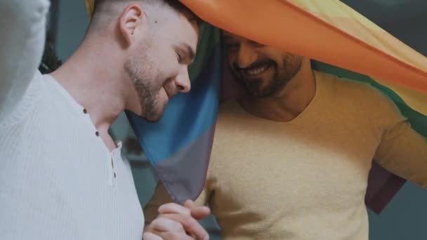 Close up, homoseksueel man paar hebben plezier en flirten bedekt met regenboog vlag — Stockvideo