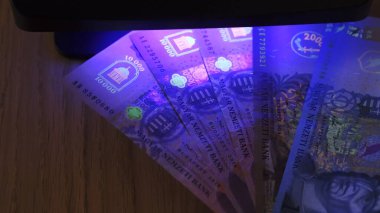 Varşova, Polonya 01.01.2021 Macar forint UV lambası kalpazanlık karşıtı test. Işık saçan mürekkep desenleri ultraviyole ışığın altında görünür hale geldi. Kapat. 