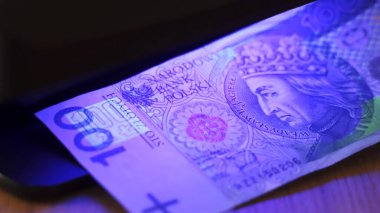 Varşova, Polonya 01.01.2021 UV lambası altında Polonya Zloti banknotu - sahte parayı tanımak için test ekipmanları