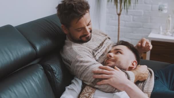 Glückliches homosexuelles männliches Paar verbringt Zeit miteinander, kuschelt und entspannt auf der Couch — Stockvideo
