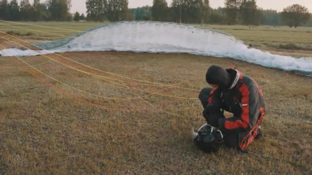 Paraglider dalam keselamatan memakai penyesuaian helm di depan parasut. Bersiap untuk lepas landas — Stok Video