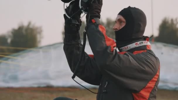 Portrait of paraglider putting on his safety helmet in front of the parachute — Stock Video