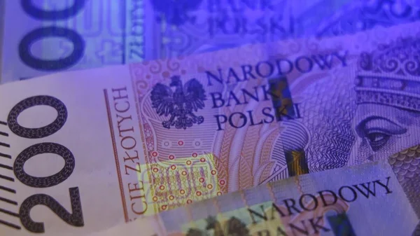 Varsó, Lengyelország 01.01.2021 Lengyel zloty az UV lámpa alatt. Papírpénzt tesztel a hamisítási koncepcióhoz. extrém közeli kép a pénz biztonsági funkciók — Stock Fotó