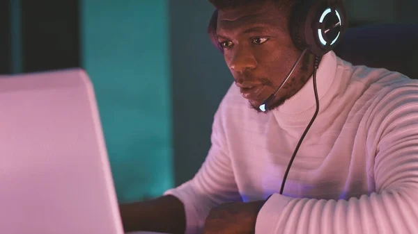 Hombre negro con auriculares iluminados, jugador o comentarista de juegos — Foto de Stock