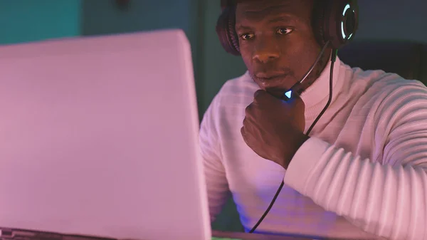 Hombre creativo negro, con auriculares iluminados trabajando hasta tarde en la noche —  Fotos de Stock