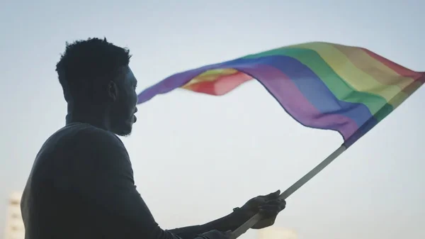 Fekete férfi lengetett szivárvány zászlót szimbólumok között tiltakozók LMBT jogok, büszkeség események — Stock Fotó