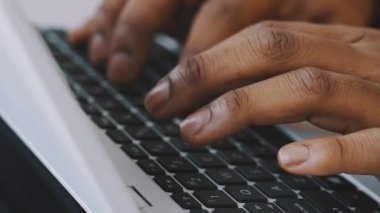 Laptop klavyesinde yazı yazan tanınmayan Afro-Amerikan iş adamının yakın çekim görüntüleri.
