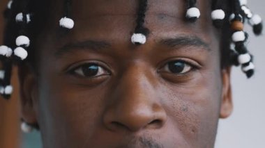 Yakından, kendinden emin Afro-Amerikalı örgülü siyah adamın gözleri kameraya bakıyor.