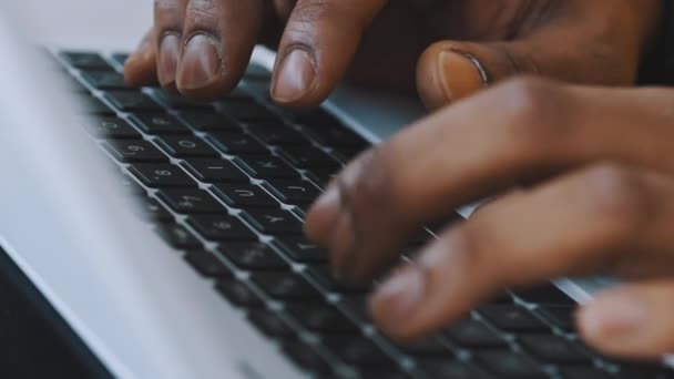 Close-up, handen van een zwarte man die typt op het laptop toetsenbord. Concentratie op afstand — Stockvideo