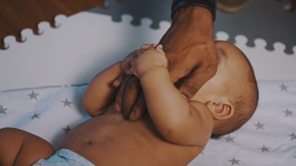 Cute mulatto baby boy playing with hand of his father. Multiracial family concept — Stock Video