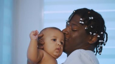 Mutlu aile kavramı. Genç Afrikalı Amerikalı siyah baba melez bebeğini öpüyor.