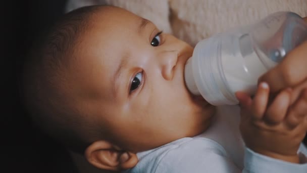 Close-up, donkere huid baby drinken zijn baby melk uit de fles — Stockvideo