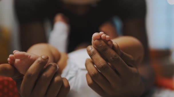 Acercaos, pies de bebé. El padre y el hijo se unen. Hombre afroamericano jugando con los pies pequeños de su bebé mulato — Vídeo de stock