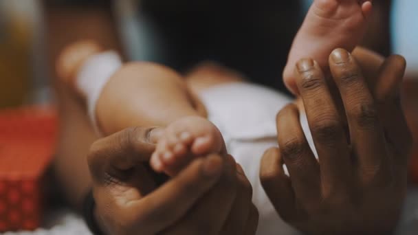 Zwarte vader die met babyvoeten speelt. Sluiten slow motion — Stockvideo