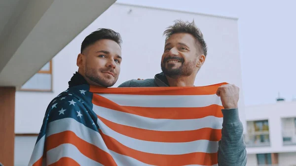 Gelukkig gay paar in liefde knuffelen op het balkon bedekt met usa vlag — Stockfoto