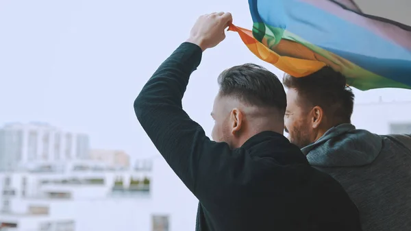 Fechar, feliz casal homossexual masculino acenando bandeira do arco-íris — Fotografia de Stock