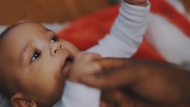 Adorável bebê segurando a mão do pai. Mulato bebê brincando com os pais mão. de perto — Vídeo de Stock