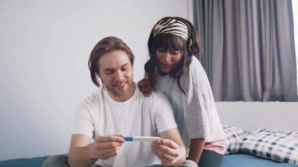 Entusiasmado jovem casal esperando pelos resultados do teste de gravidez. Teste positivo. Casal multiracial esperando bebê — Vídeo de Stock