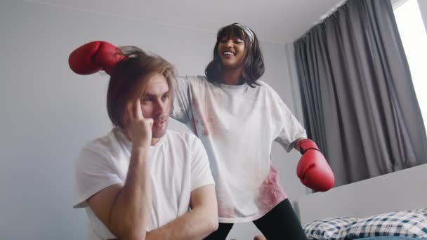 Mulher com luvas de boxe brincando com namorados cabelo longo tentando animá-lo — Vídeo de Stock