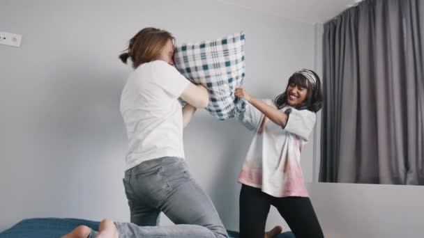 Luta de almofadas. feliz jovem casal multirracial lutando com travesseiros no quarto. — Vídeo de Stock