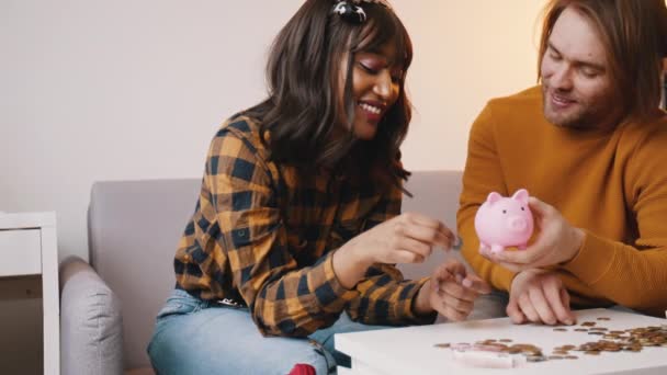 Heureux couple de jeunes mariés heureux de mettre des pièces dans la tirelire. Épargner et construire la richesse concept — Video