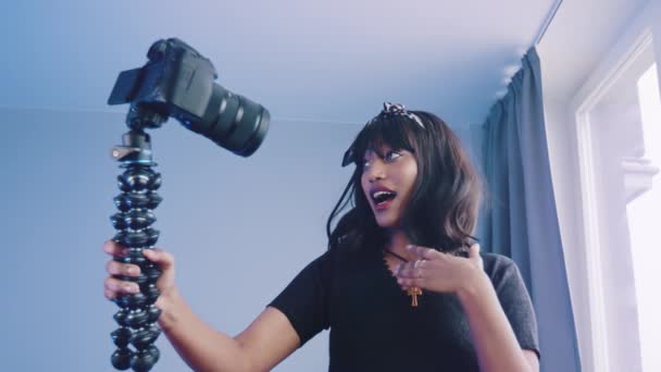 Vrolijke jonge Afro-Amerikaanse vrouwelijke blogger houden camera en opnemen van video voor vlog terwijl staan in de buurt van het raam — Stockvideo