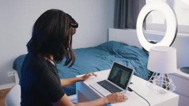 Genç bir kadın, yatak odasında video kaydediyor. Kilitleme sırasında modern teknoloji ve internetin kullanımı
