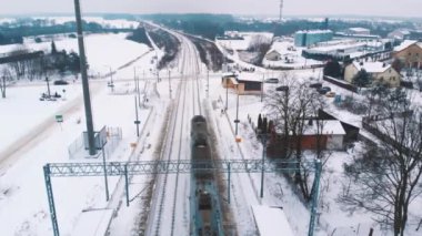 Tren karla kaplı demiryolunun üzerinden geçiyor. Havadan