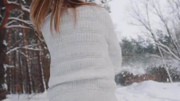 Ung kvinna i grå tröja snurrar medan hon håller första snön i händerna. Inget ansikte — Stockvideo
