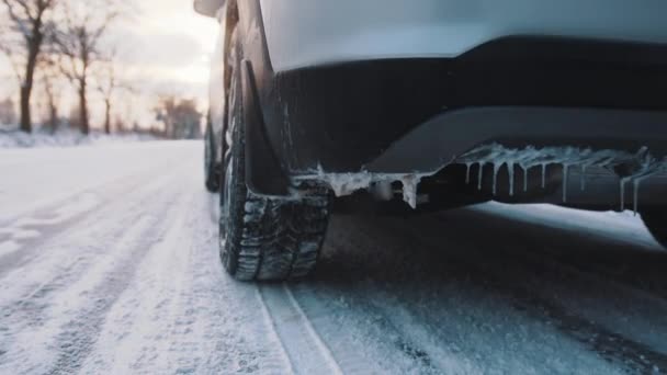 Auto congelata guida sulla strada coperta di neve vicino alla foresta lasciando dietro di sé fumo. — Video Stock