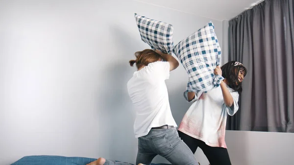 Glada unga par som har kuddar slåss i sovrummet. Kärlek och tillgivenhet — Stockfoto