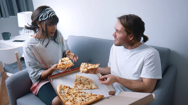 Gelukkig jong multi raciaal koppel dat pizza eet en zich ontspant op de bank. Langzame beweging — Stockfoto