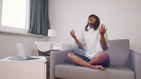 Meditação e atenção plena. Jovem mulher negra espiritual sentada no sofá meditando ou orando — Fotografia de Stock