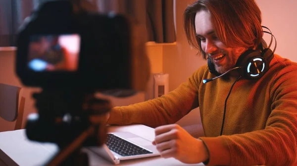Mladý muž se sluchátky pracuje na notebooku při nahrávání videa na kameru — Stock fotografie