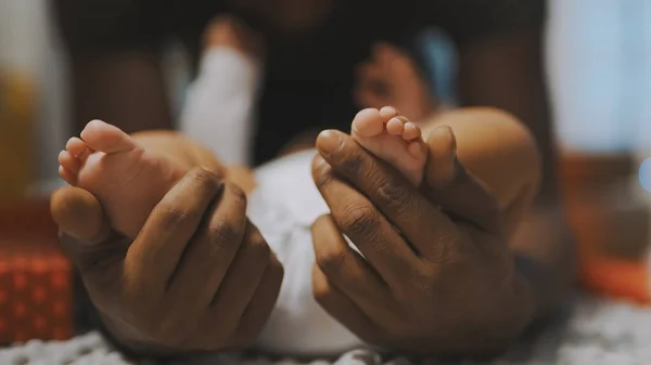 Närbild, babyfötter. Far och son förenas. Afrikansk amerikansk man leker med små fötter av sin mulattbebis — Stockfoto