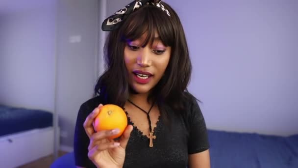 Beautiful young african american black woman vlogging about fruit and dieting. Holding orange and pack of strawberries — Stockvideo