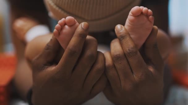 黒い父親が赤ん坊の足で遊んでいる。スローモーションを閉じます — ストック動画