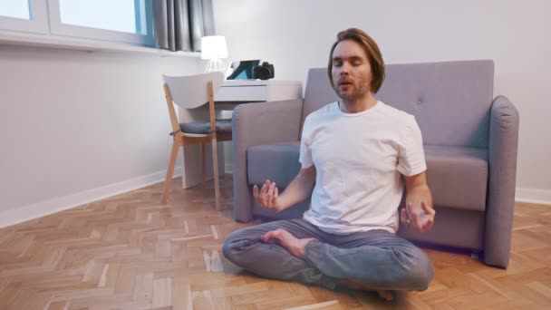 Genç beyaz bir adam dairesinde meditasyon yapıyor. Nefes alma tekniği — Stok video