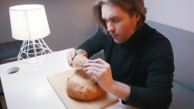 Kafkasyalı genç bir adam, elinde ekmeğin huzuruyla ona bakıyor. Yavaş çekim