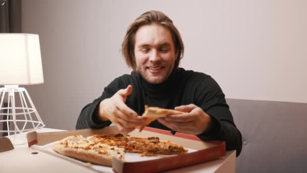 Young caucasian man eating pizza and smiling — Stock Video